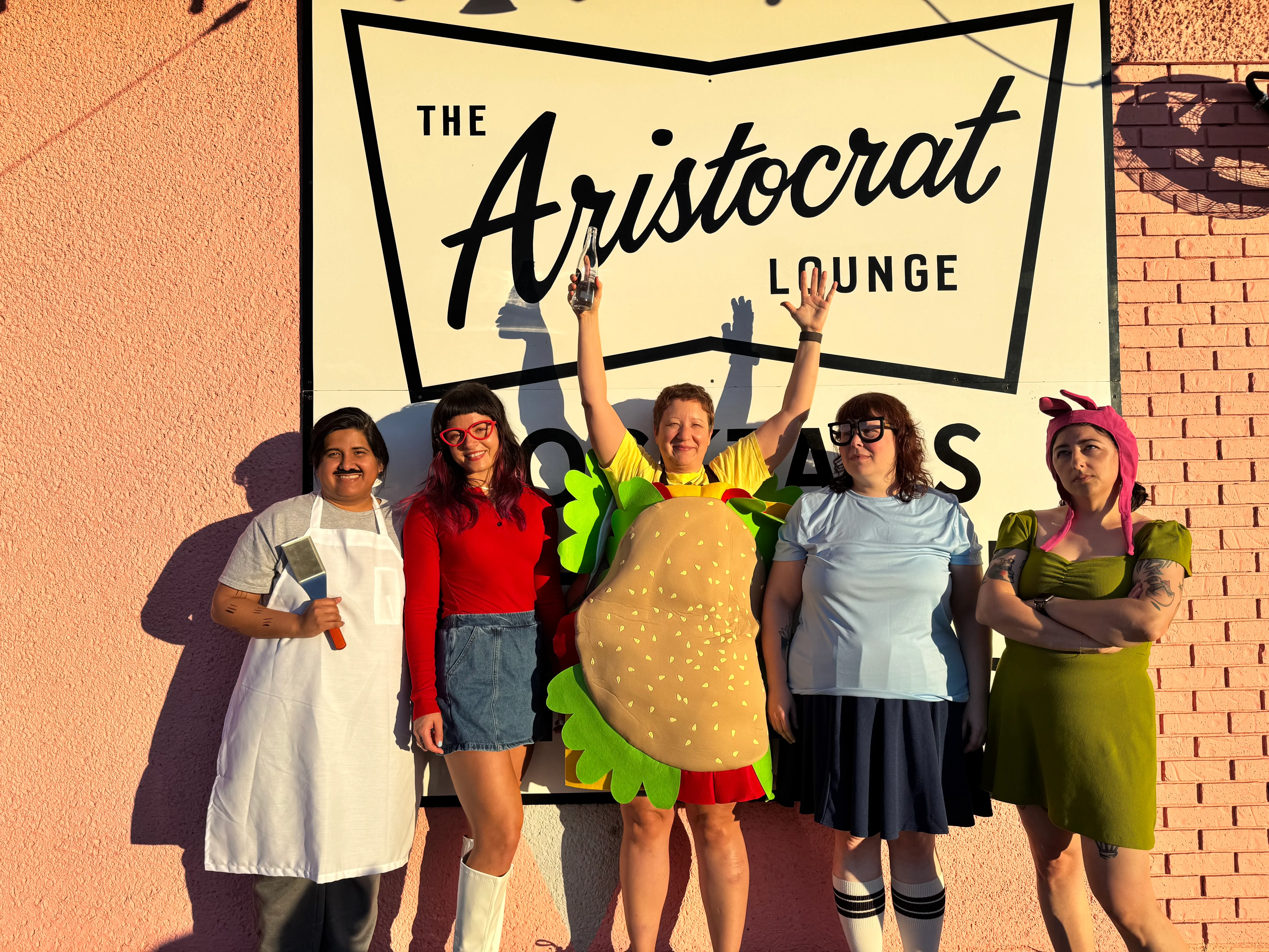 Sea Hagzzz, an all-women surf rock band, posed in Bob's Burgers Halloween costumes in front of the Aristocrat Lounge sign in Austin, Texas.
